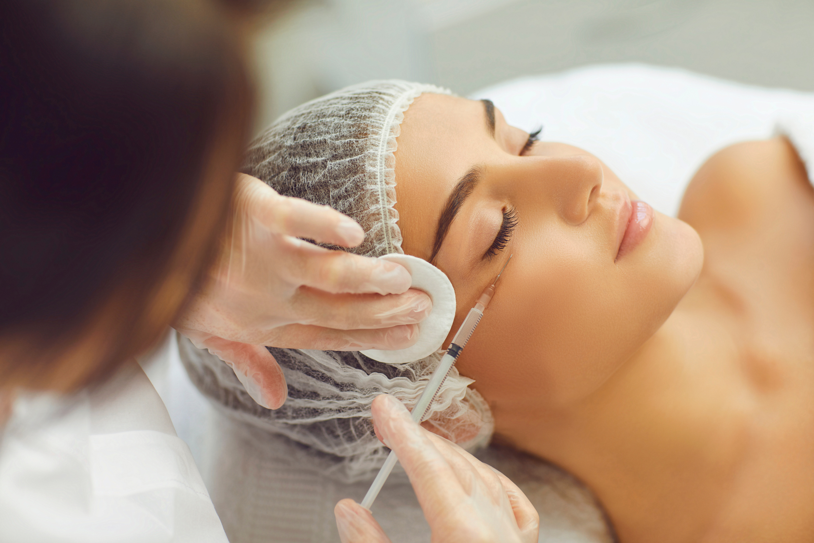 Female Beautician Makes Injections to a Girl's Cheekbone to Smooth Facial Wrinkles.